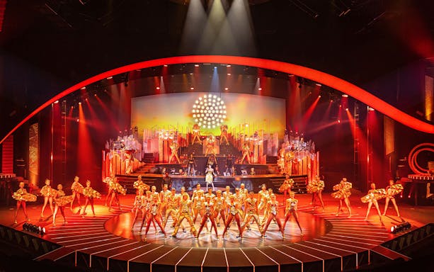 Performers in vibrant costumes on stage at ARISE Grand Show.