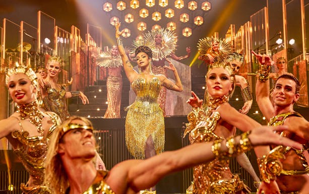 Performers in gold costumes on stage at ARISE Grand Show.