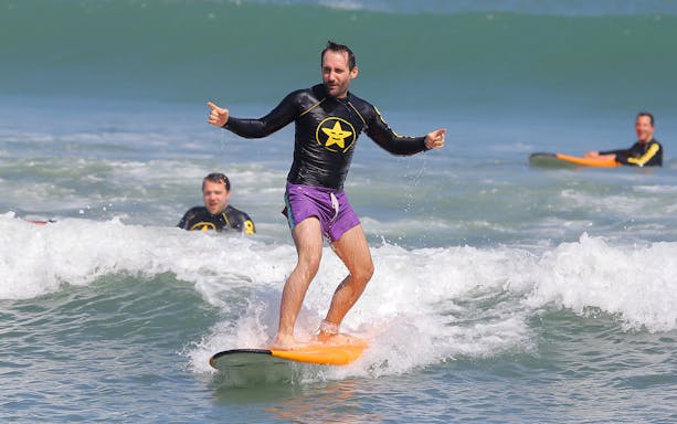 Surfer balancing on a wave during a lesson at Odysseys Surf School.