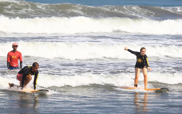 Surf lesson participants riding waves at Odysseys Surf School.