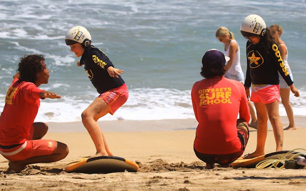 Surf instructor teaching kids at Odysseys Surf School on the beach.