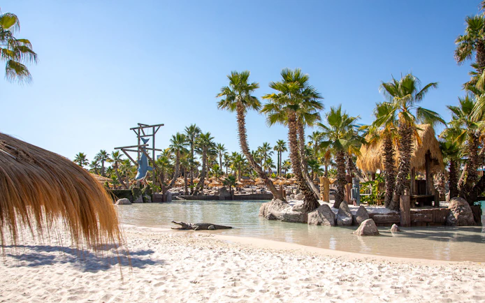 Caribe Bay water park with palm trees, sandy beach, and lagoon.
