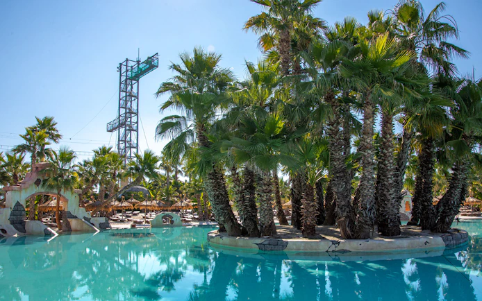 Caribe Bay water park with palm trees and pool, featuring a tall diving platform.