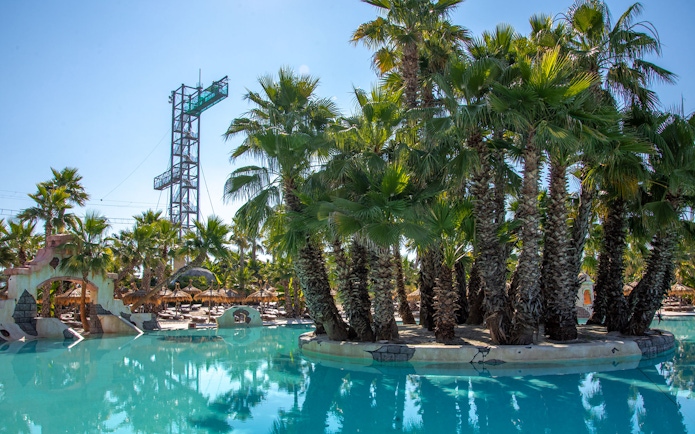 Caribe Bay water park with palm trees and pool, featuring a tall diving platform.