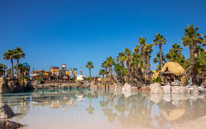 Caribe Bay water park entrance with palm trees and themed structures.