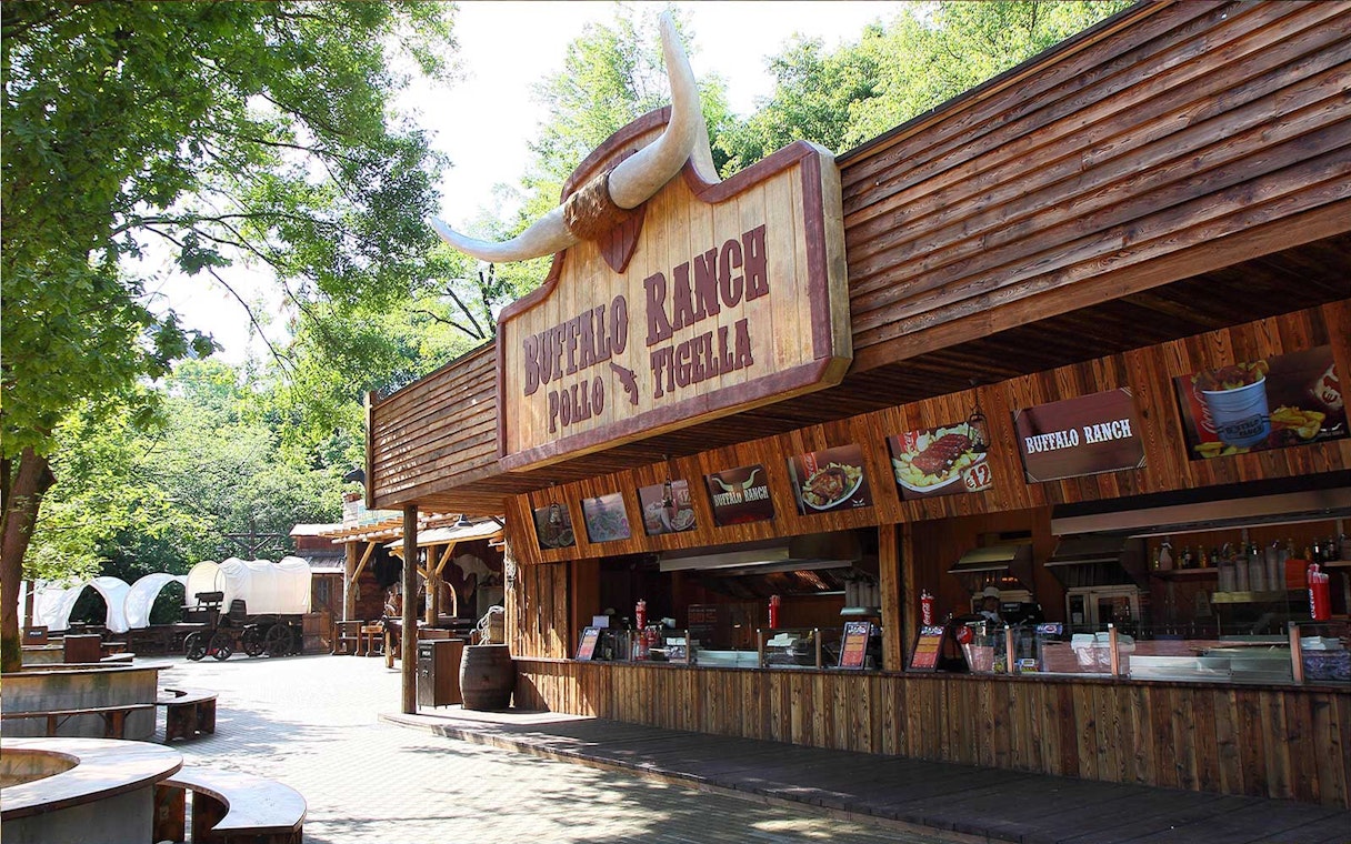 Buffalo Ranch food stand at Gardaland Park with covered wagons nearby.