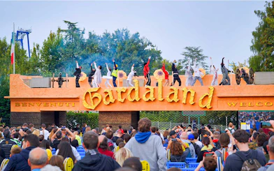 Performers on stage at Gardaland Park entrance, Verona, Italy, with a crowd watching.