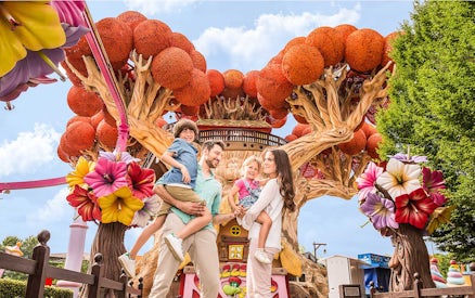 Family enjoying time at Gardaland Park with colorful tree attraction.