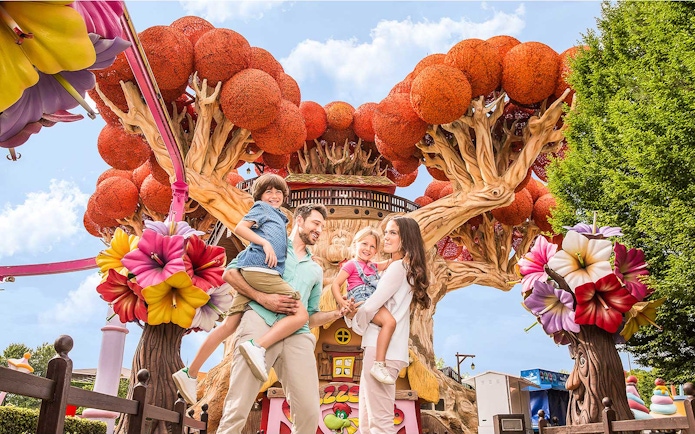 Family enjoying time at Gardaland Park with colorful tree attraction.