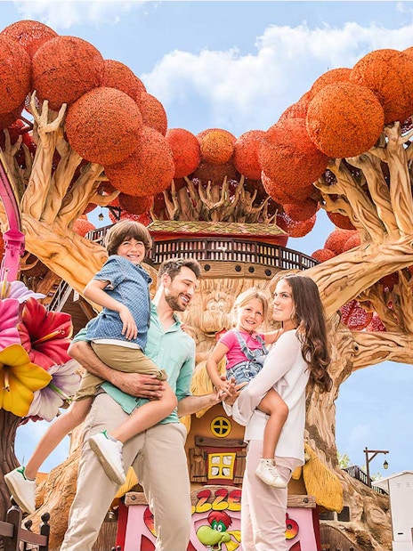 Family enjoying time at Gardaland Park with colorful tree attraction.