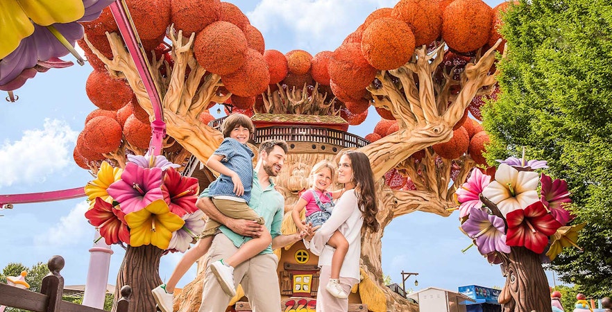 Family enjoying time at Gardaland Park with colorful tree attraction.
