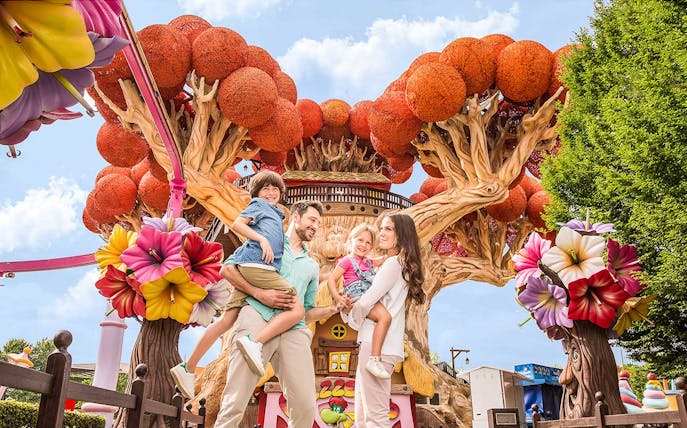 Family enjoying time at Gardaland Park with colorful tree attraction.