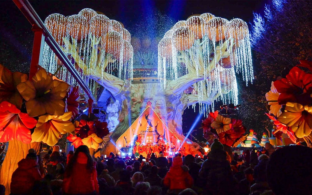 Gardaland Park night show with illuminated tree and crowd.