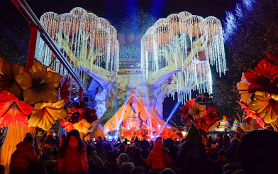 Gardaland Park night show with illuminated tree and crowd.