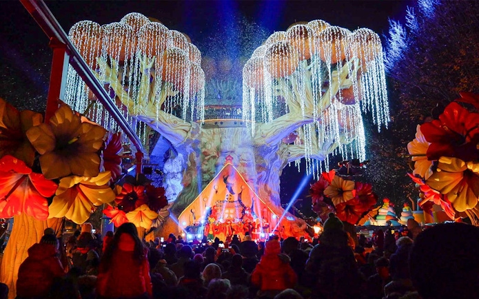 Gardaland Park night show with illuminated tree and crowd.