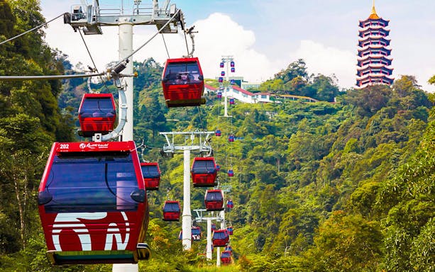 Genting Highlands cable cars ascending through lush green hills with a pagoda in the background.