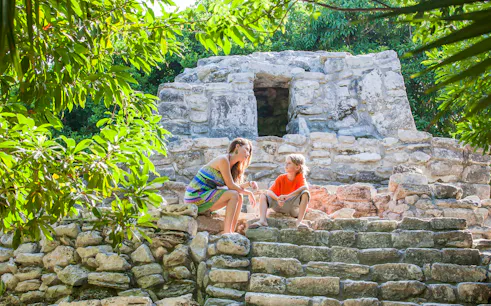 Visitors exploring ancient ruins in Tulum, surrounded by lush greenery.