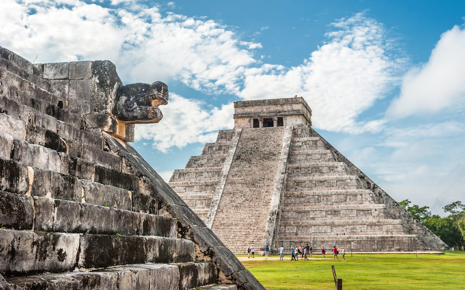 Chichén Itzá pyramid with serpent sculpture, tourists exploring the site.