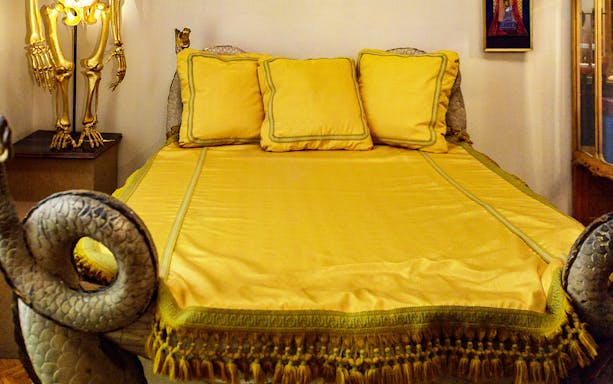 Yellow bed with ornate headboard and skeleton lamp at Dalí Museum, Cadaqués.
