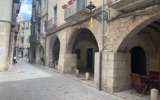 Historic stone archways and narrow street in Girona, Spain.