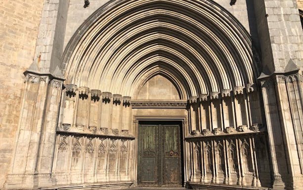 Gothic cathedral entrance in Girona with ornate arches and stone carvings.