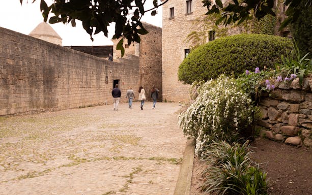 Visitors walking through historic stone courtyard in Girona.