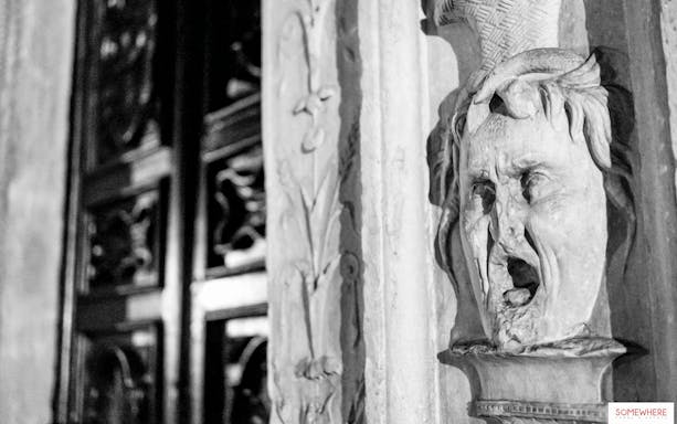 Stone face sculpture on a building during the Torino Magica guided tour.