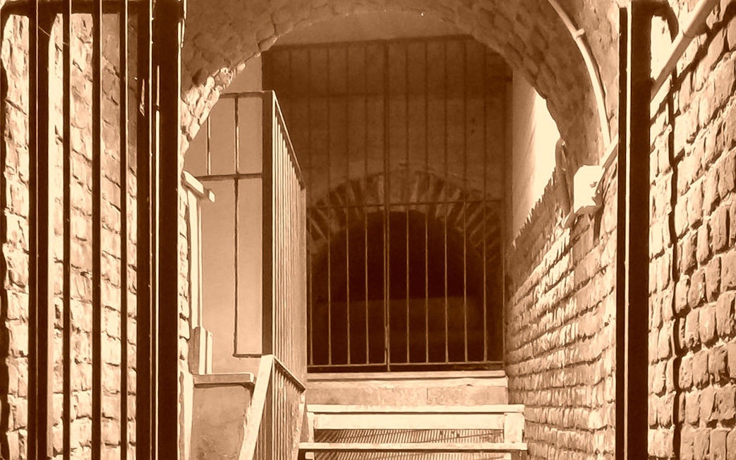 Underground passage with brick walls and metal gate in Turin.