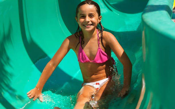 Child enjoying a water slide at Aquopolis Cullera.