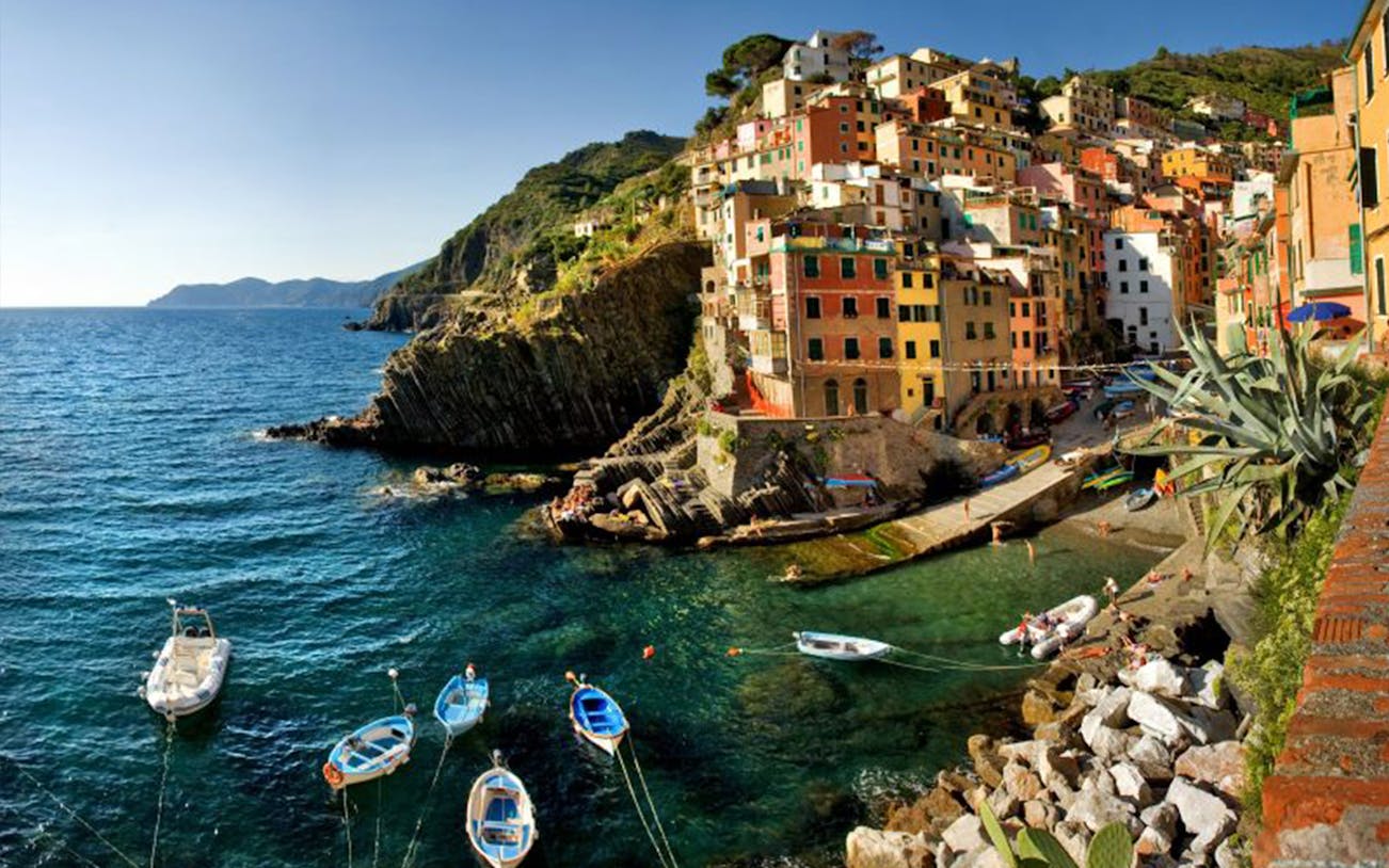 Colorful cliffside village of Riomaggiore, Cinque Terre, with boats in the harbor.