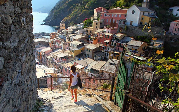 Person walking down steps towards Vernazza village in Cinque Terre, Italy.