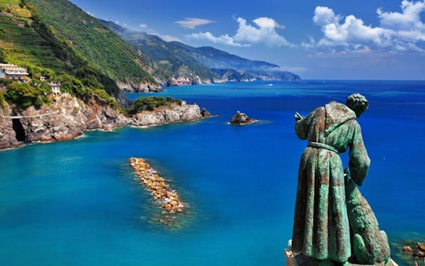 Statue overlooking the coastline of Cinque Terre with cliffs and blue sea.