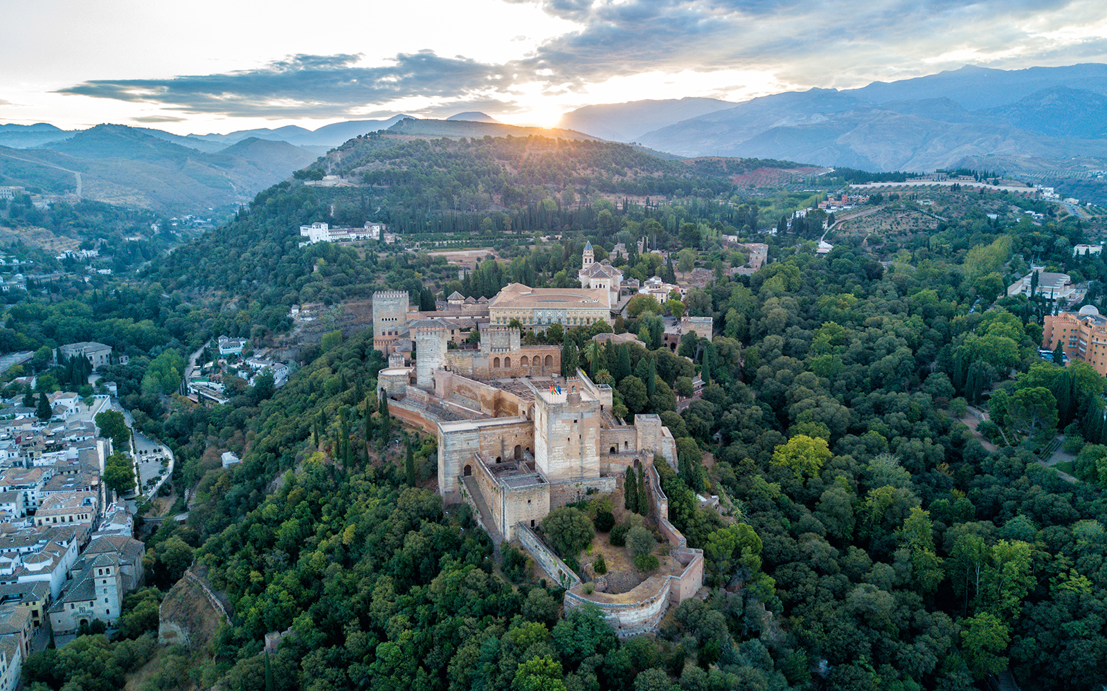 Aerial view of the Alhambra surrounded by lush greenery in Granada, Spain.