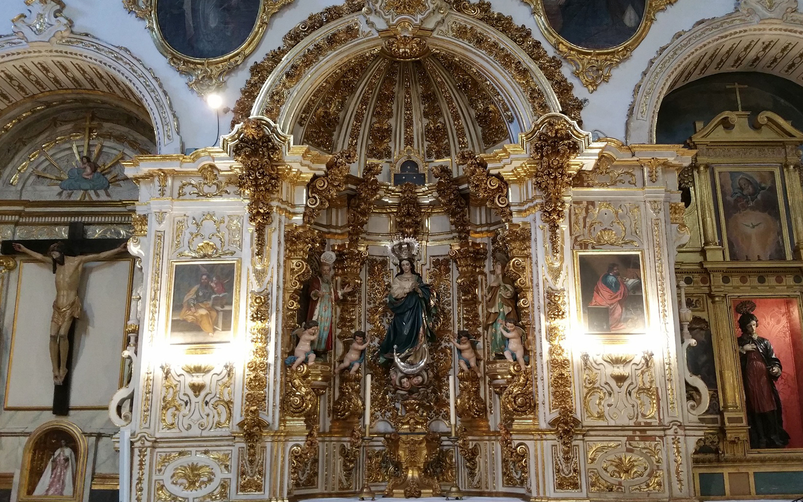 Altar with ornate gold detailing and religious statues inside Granada Cathedral.