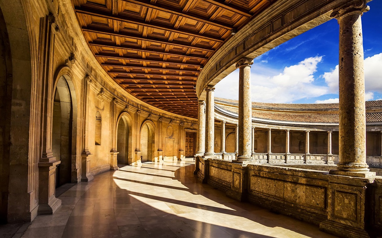 Alhambra's circular courtyard with stone columns and arches in Granada, Spain.