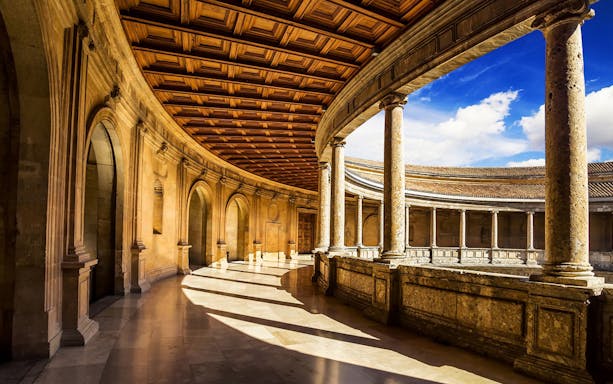 Alhambra's circular courtyard with stone columns and arches in Granada, Spain.
