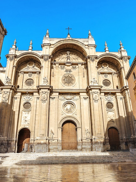 Granada Cathedral facade with surrounding buildings on a sunny day.