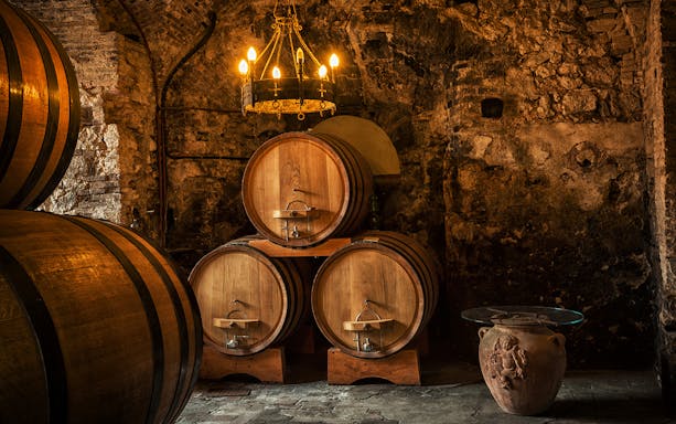 Wine barrels in a rustic Tuscan cellar on the Tuscany Wine and Olive Oil Trail tour.
