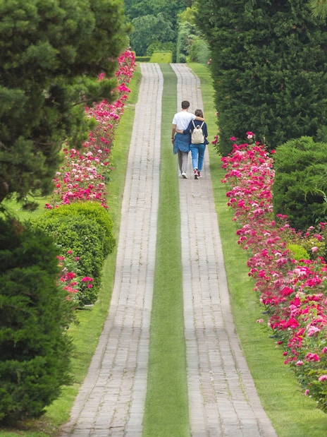 Couple walking along a flower-lined path in Parco Giardino Sigurtà, Italy.