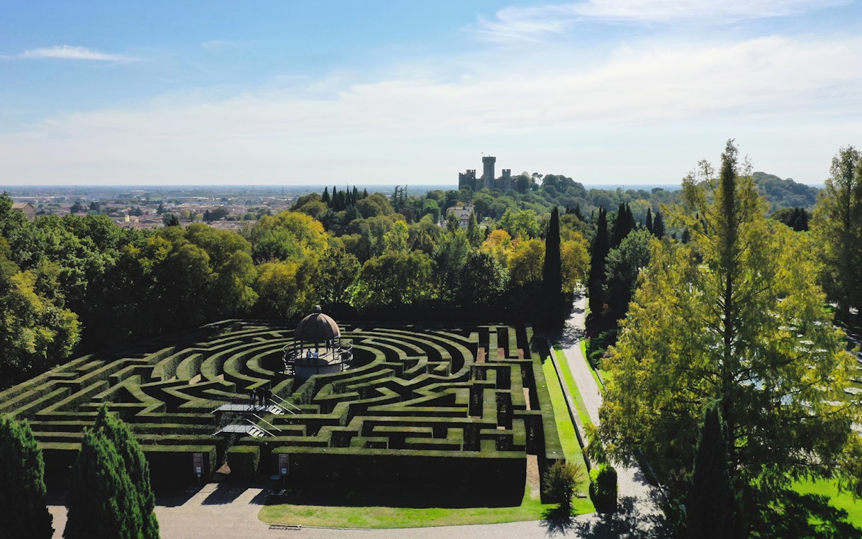 Hedge maze at Parco Giardino Sigurtà with distant view of a castle, Italy.