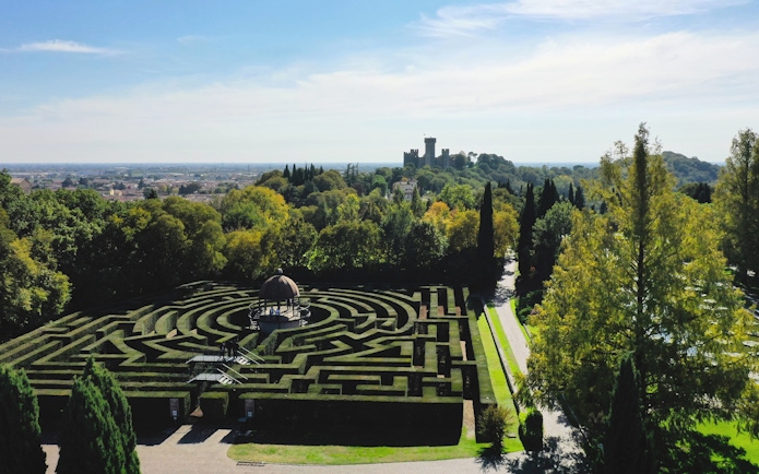Hedge maze at Parco Giardino Sigurtà with distant view of a castle, Italy.