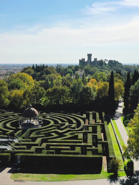 Hedge maze at Parco Giardino Sigurtà with distant view of a castle, Italy.