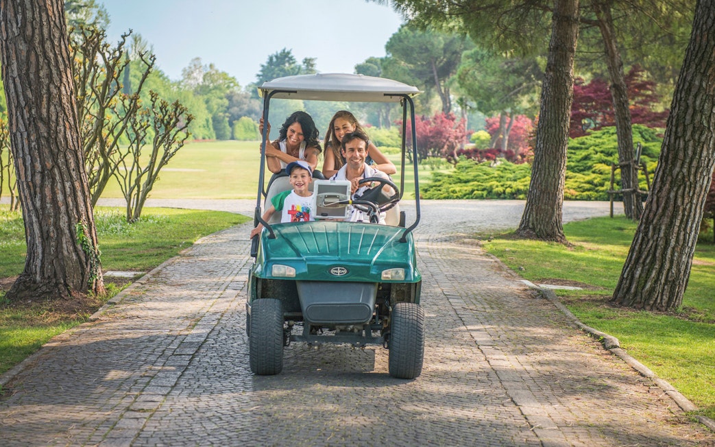 Family enjoying a golf cart ride at Parco Giardino Sigurtà, Italy.