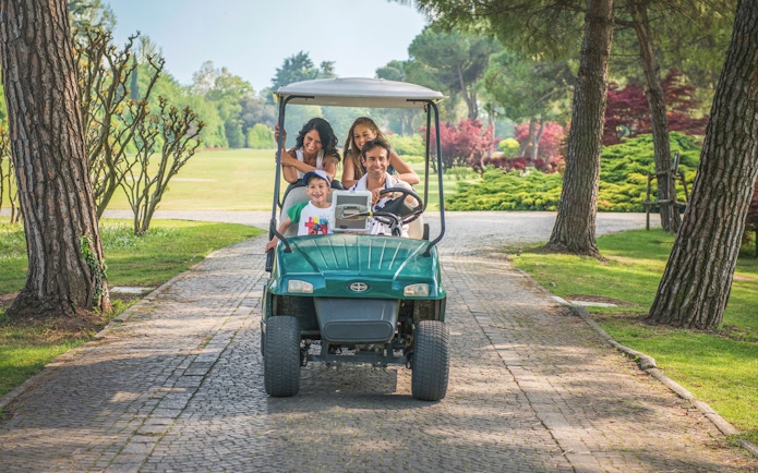 Family enjoying a golf cart ride at Parco Giardino Sigurtà, Italy.