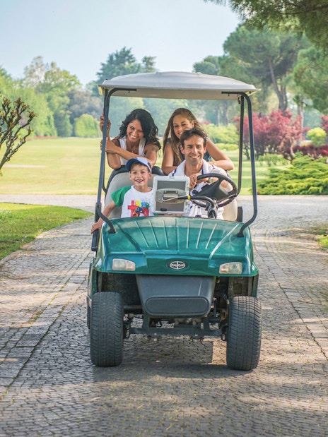 Family enjoying a golf cart ride at Parco Giardino Sigurtà, Italy.