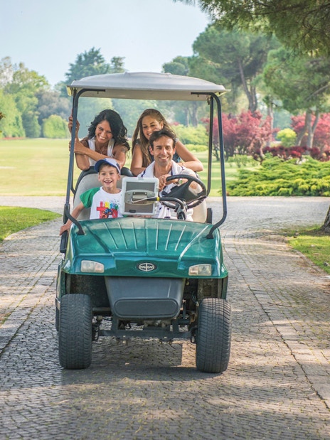 Family enjoying a golf cart ride at Parco Giardino Sigurtà, Italy.