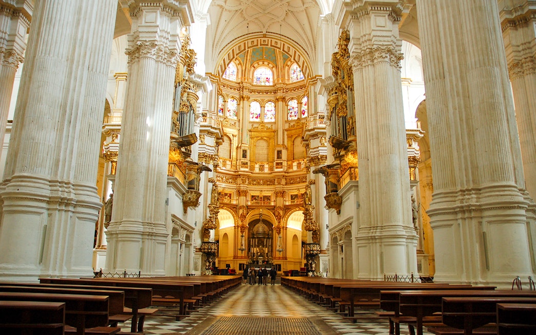 Interior of Cathedral and Royal Chapel of Granada with ornate columns and stained glass windows.