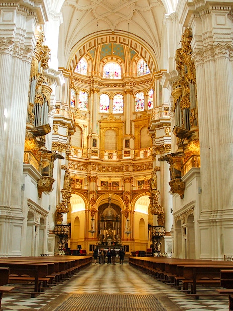 Interior of Cathedral and Royal Chapel of Granada with ornate columns and stained glass windows.