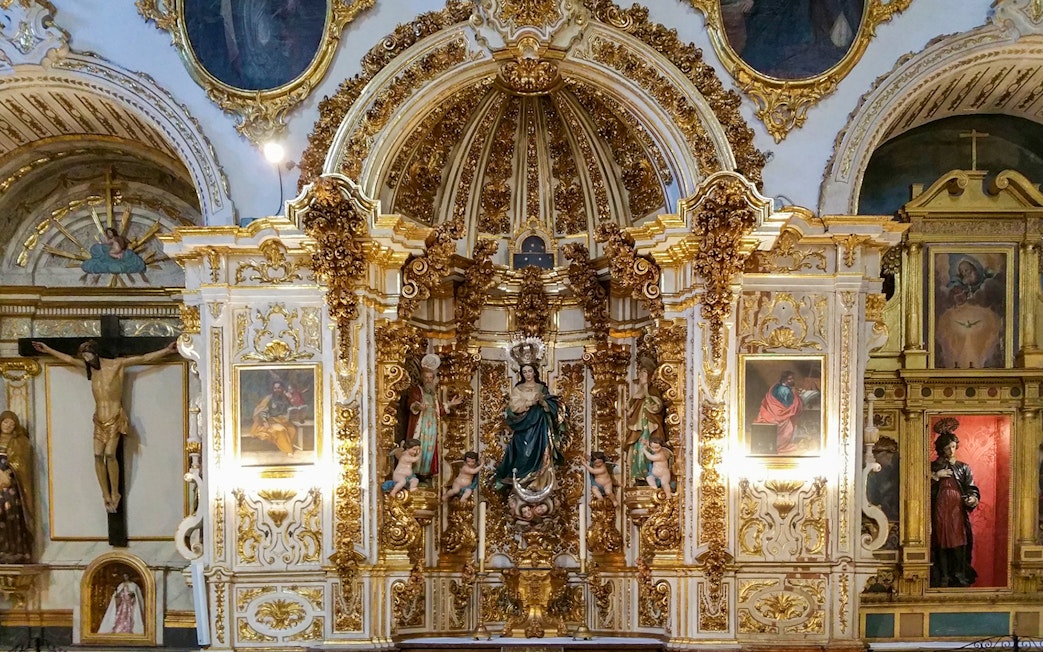 Ornate altar inside the Cathedral and Royal Chapel of Granada, featuring religious statues and gold detailing.