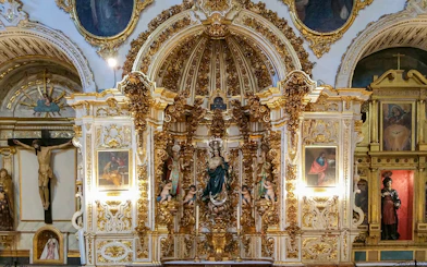 Ornate altar inside the Cathedral and Royal Chapel of Granada, featuring religious statues and gold detailing.